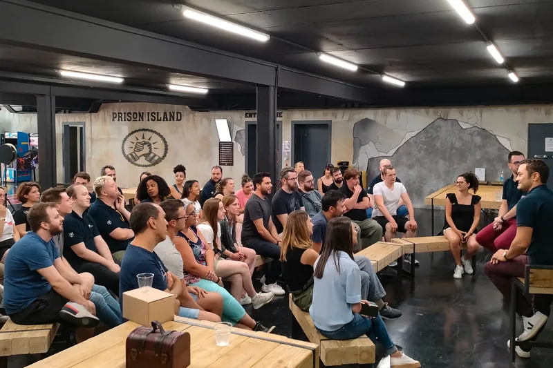 Un groupe de collègues assis sur des bancs écoute le briefing avant la partie